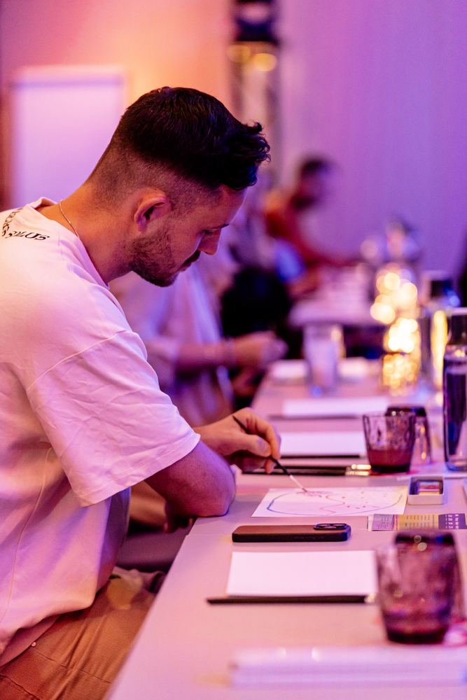 Teilnehmer malt versunken an einer langen Tafel